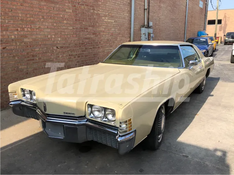 A yellow car is parked in front of a brick building.
