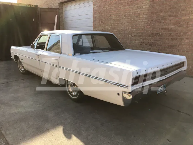 A white car is parked in front of a brick building