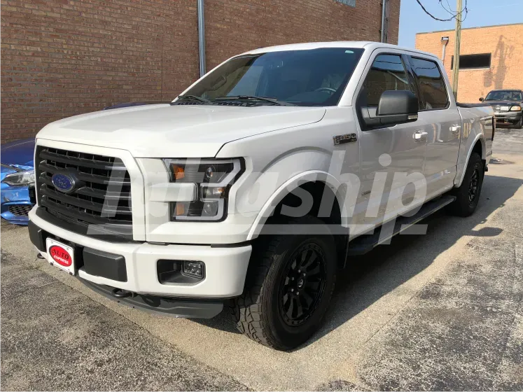 A white ford f150 truck is parked in front of a brick building.