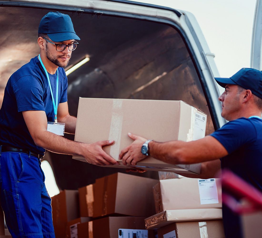 Two men are loading boxes into a van.