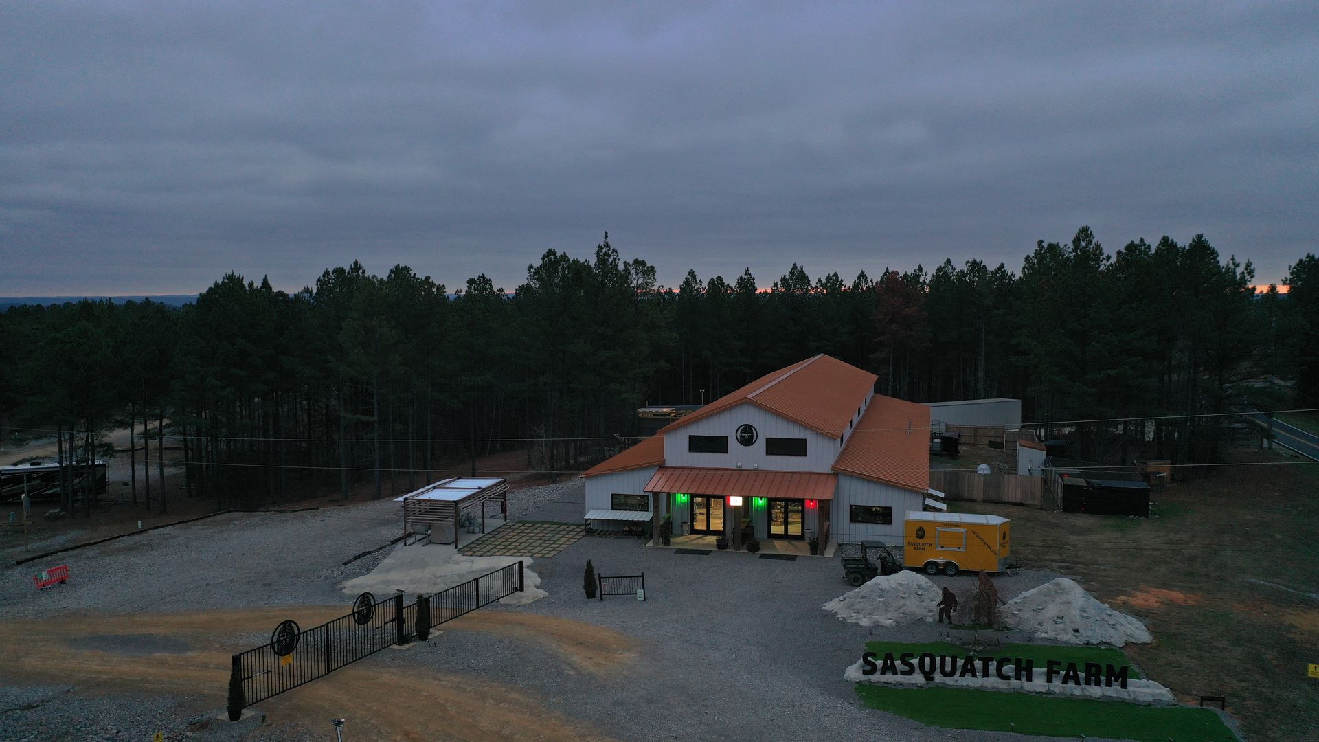 An aerial view of a building with a red roof in the middle of a forest.