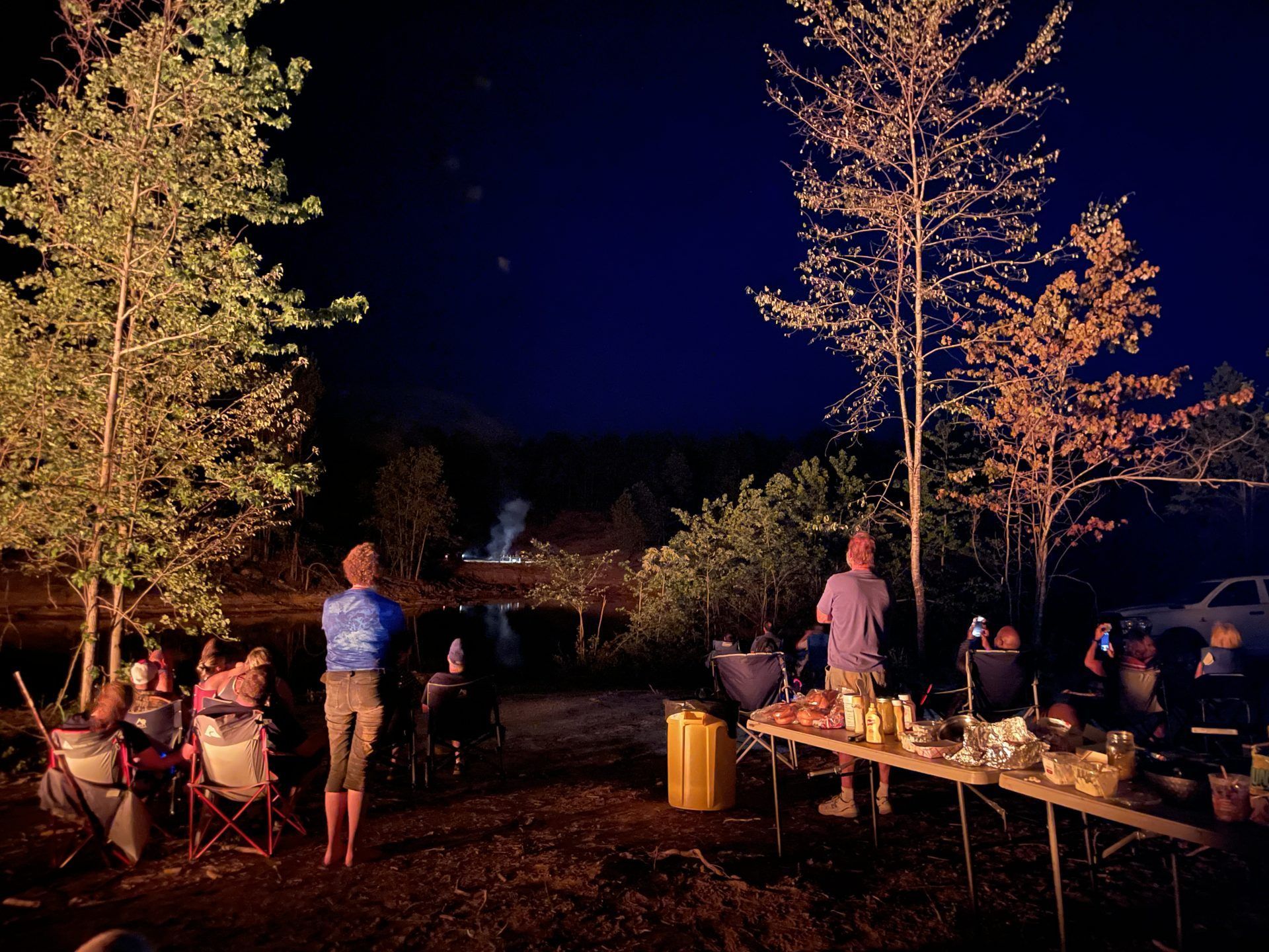 A group of people are gathered around a campfire at night