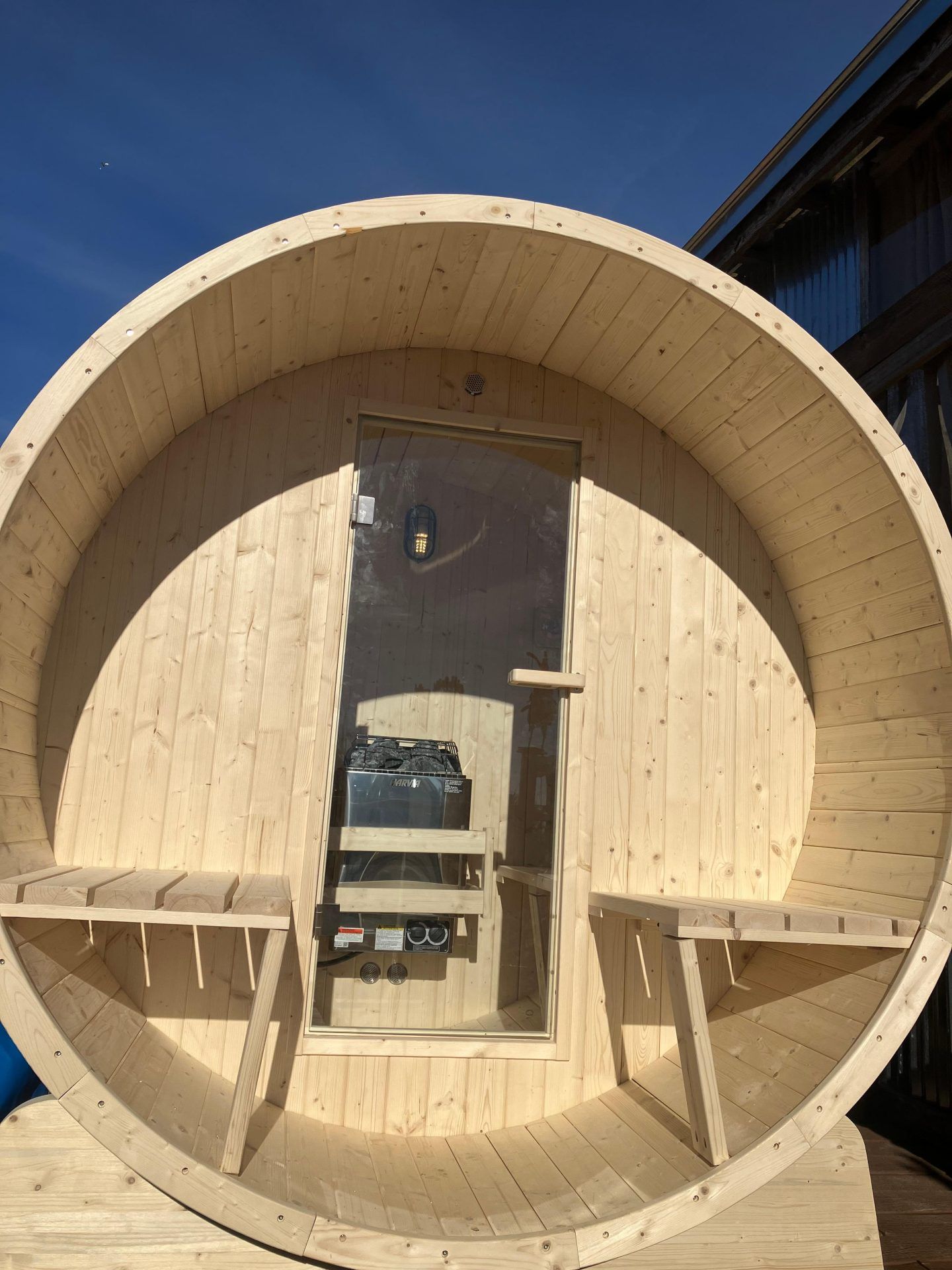 A large wooden barrel with a glass door and benches.