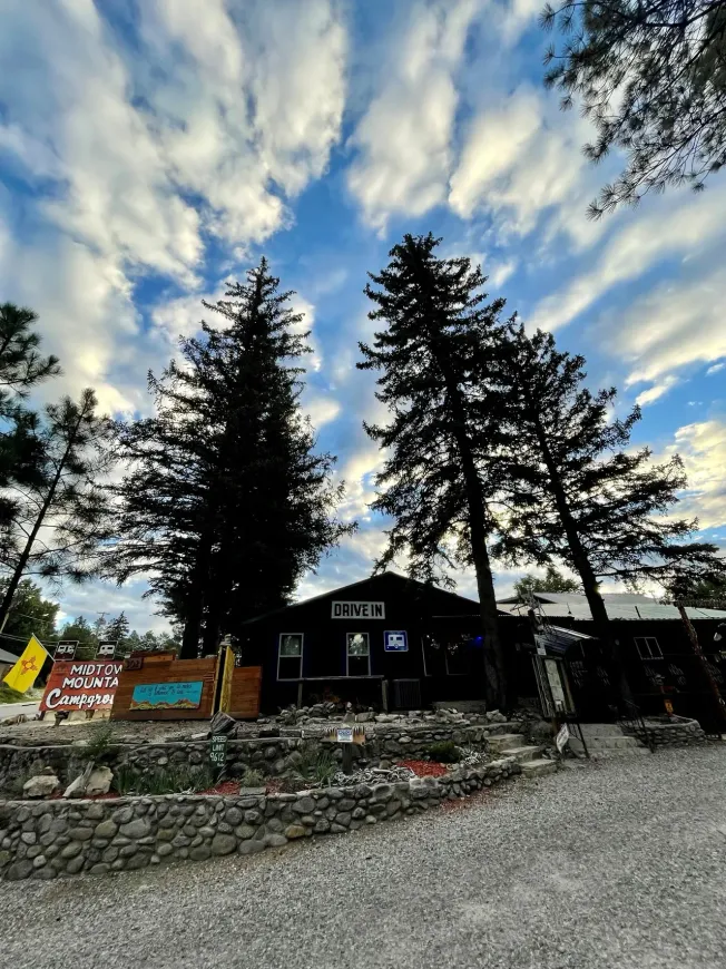 A house with trees in front of it and a blue sky with clouds