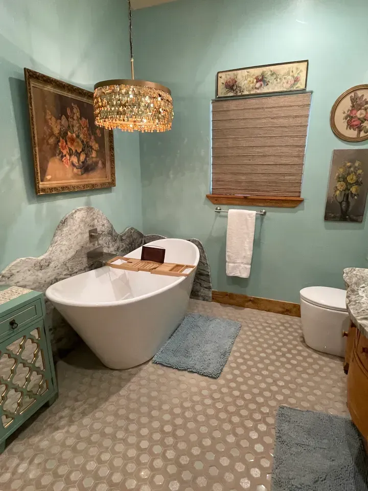 A bathroom with a tub , toilet , sink and window.