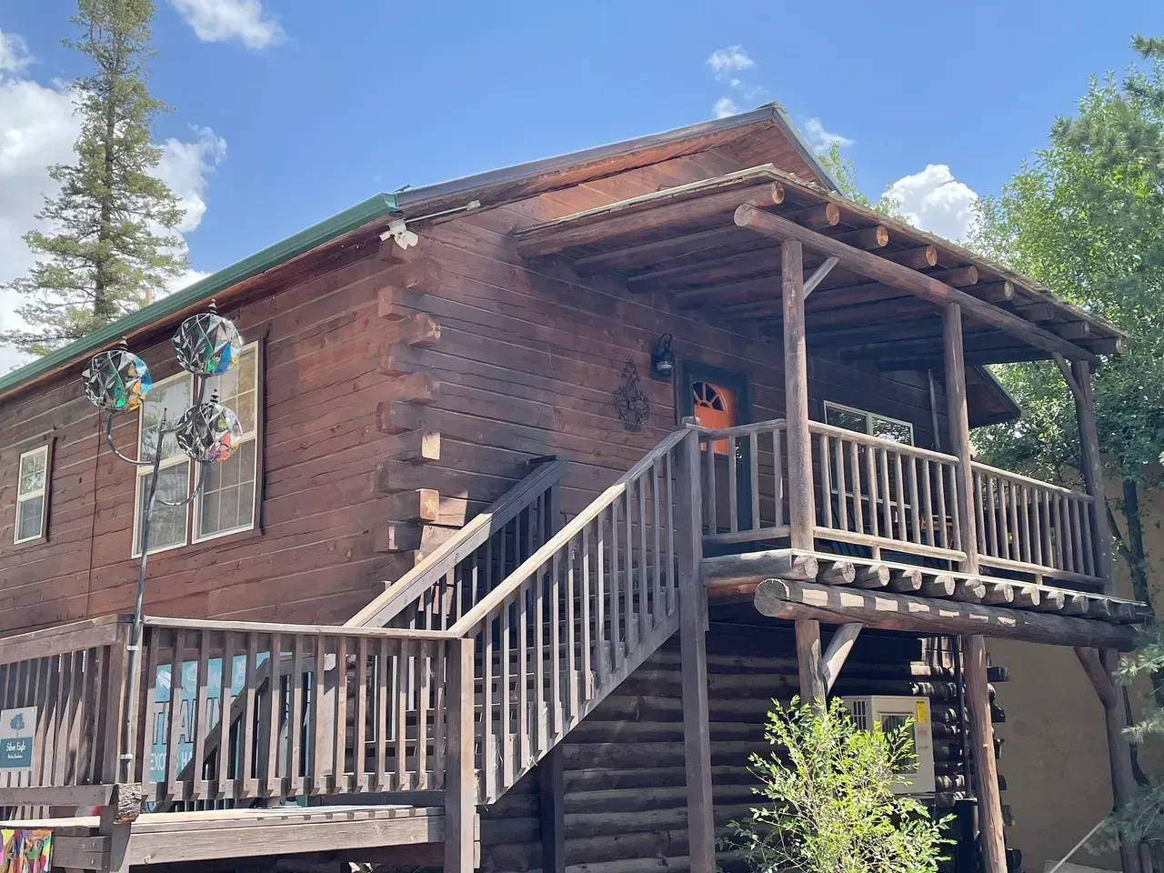 A log cabin with a large deck and stairs leading up to it.