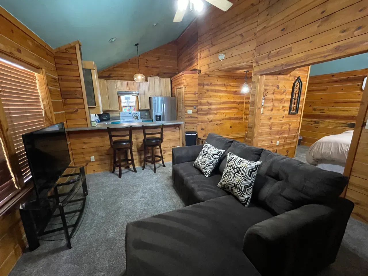 A living room with a couch and a television in a log cabin.
