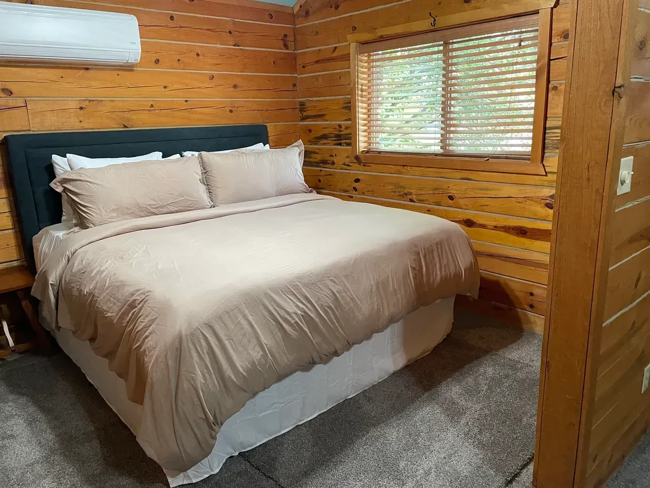 A bedroom in a log cabin with a king size bed and a window.