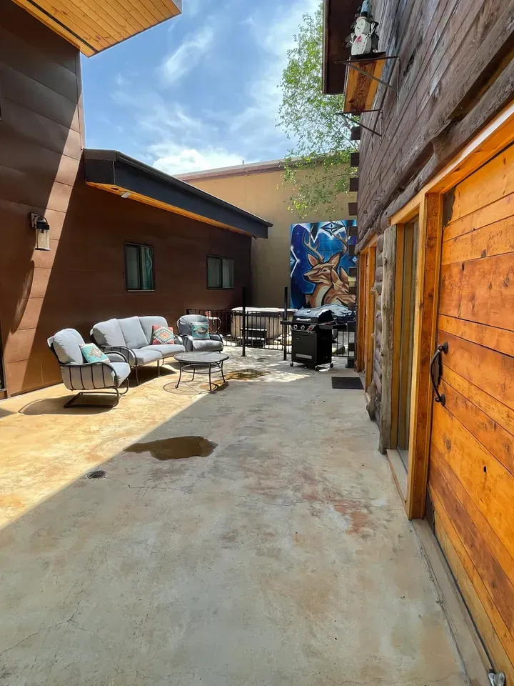 A patio with a couch , chairs , tables and a grill.