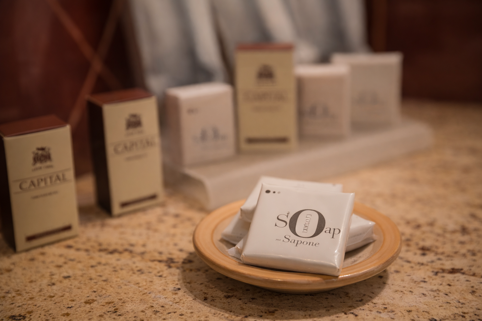 Articoli da toeletta dell'hotel su una superficie di marmo: saponi in una ciotola, shampoo e altri prodotti dietro.