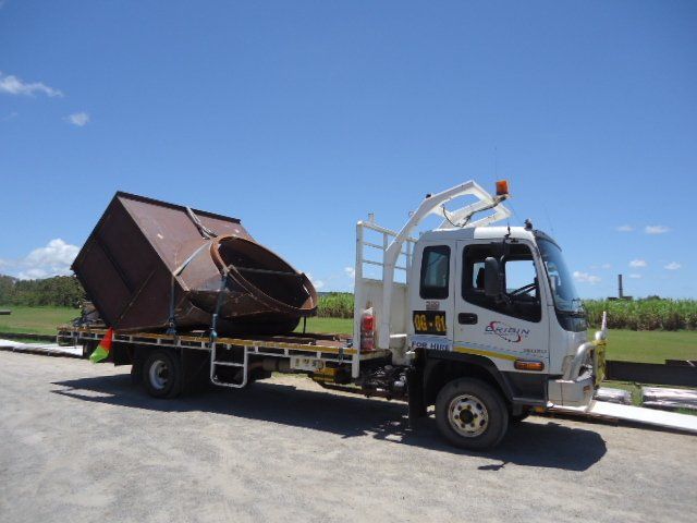 A White Truck With A Large Metal Object On The Back Is Parked On The Side Of The Road — Origin Group in Paget, QLD