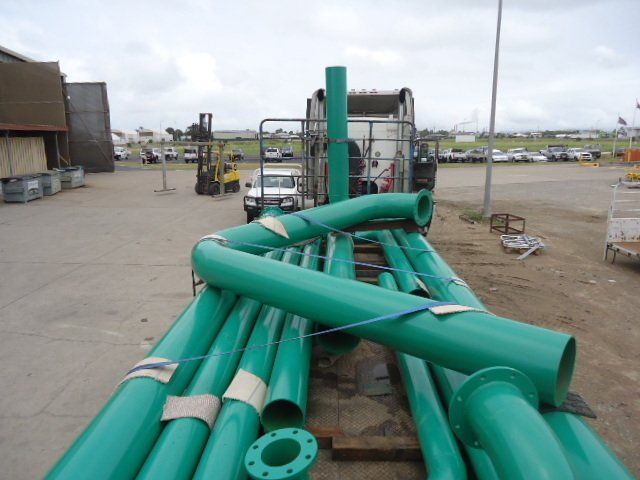 A Bunch Of Green Pipes Are Stacked On Top Of Each Other — Origin Group in Paget, QLD