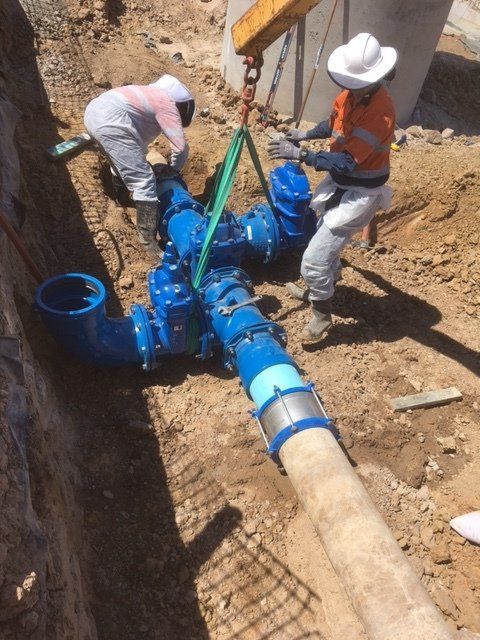 Two Men Are Working On A Pipe In The Dirt — Origin Group in Paget, QLD