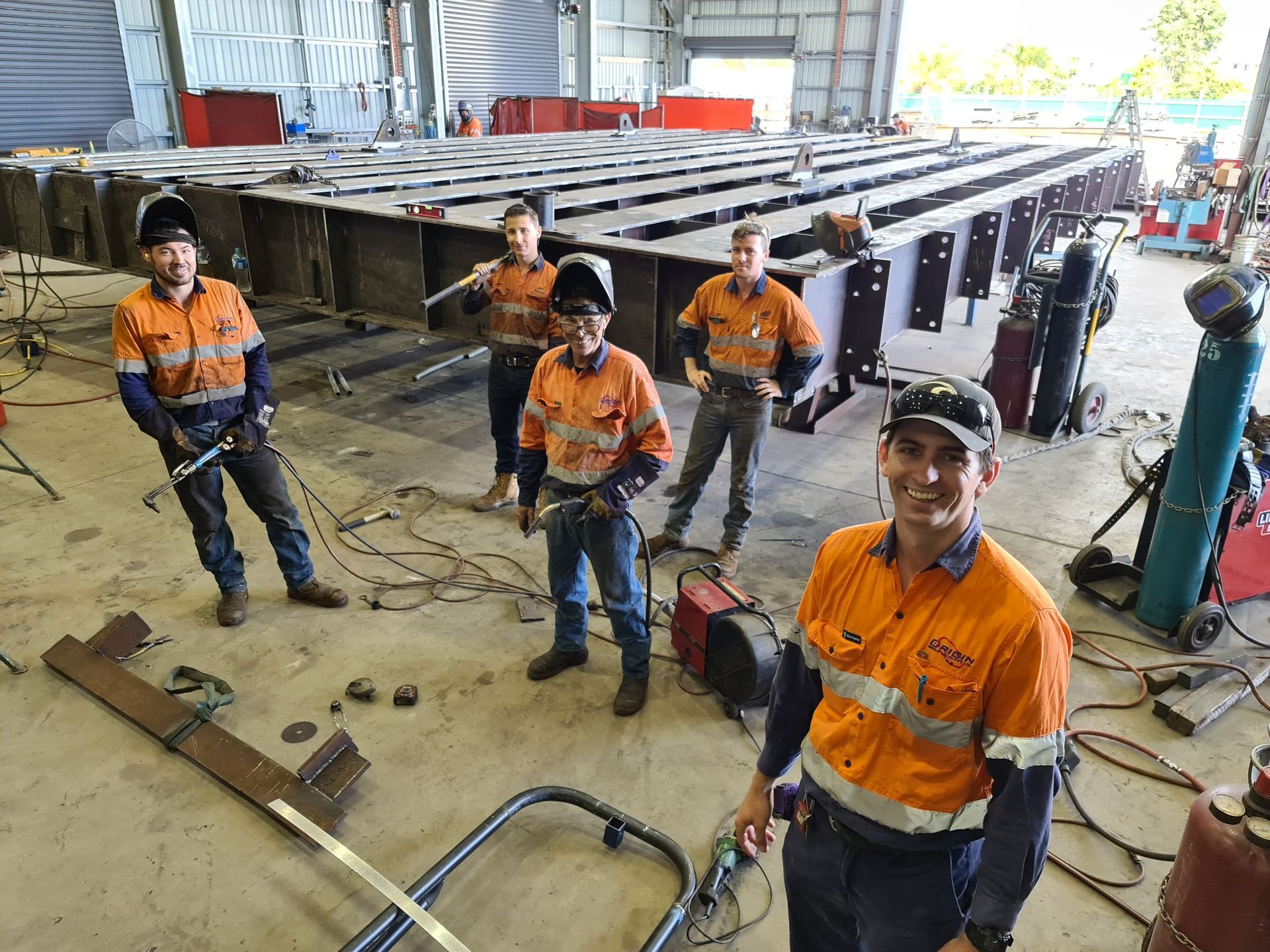 A Man In A Hard Hat Is Standing In Front Of A Tractor On A Construction Site — Origin Group in Paget, QLD