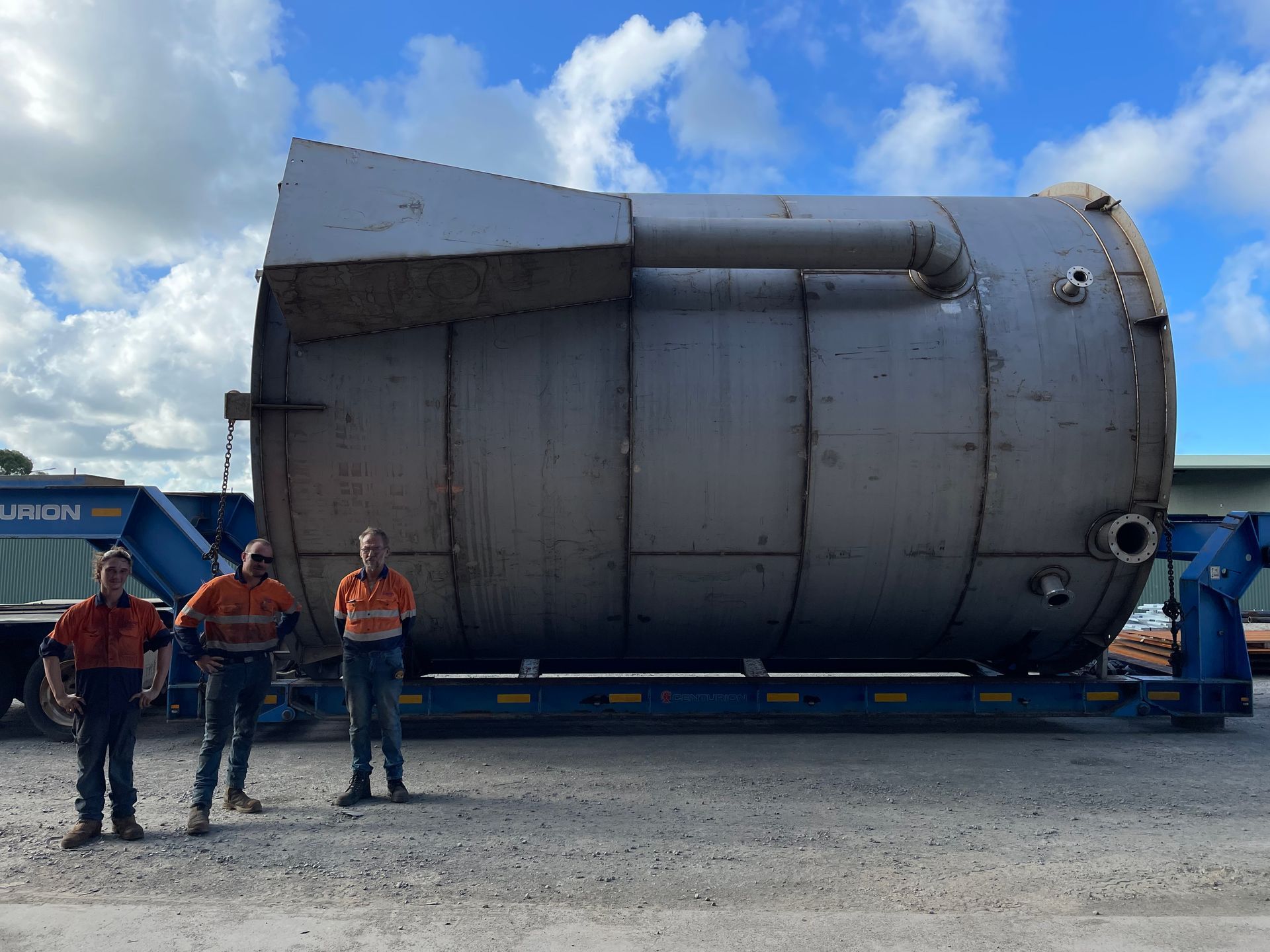 A Group Of Construction Workers Are Sitting Around A Table Looking At A Blueprint — Origin Group in Paget, QLD