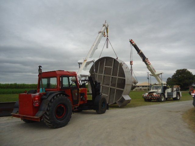 A Red Tractor Is Carrying A Large Metal Object — Origin Group in Paget, QLD