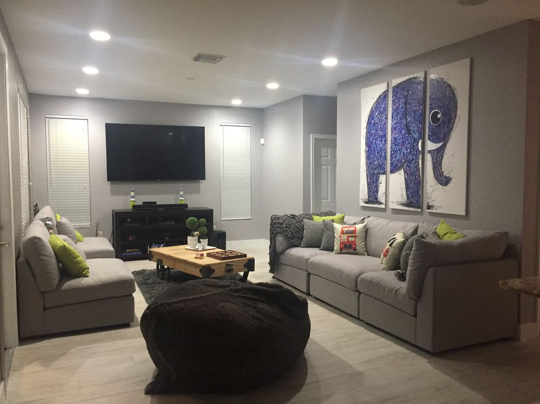 A living room with a couch , ottoman , coffee table and television.