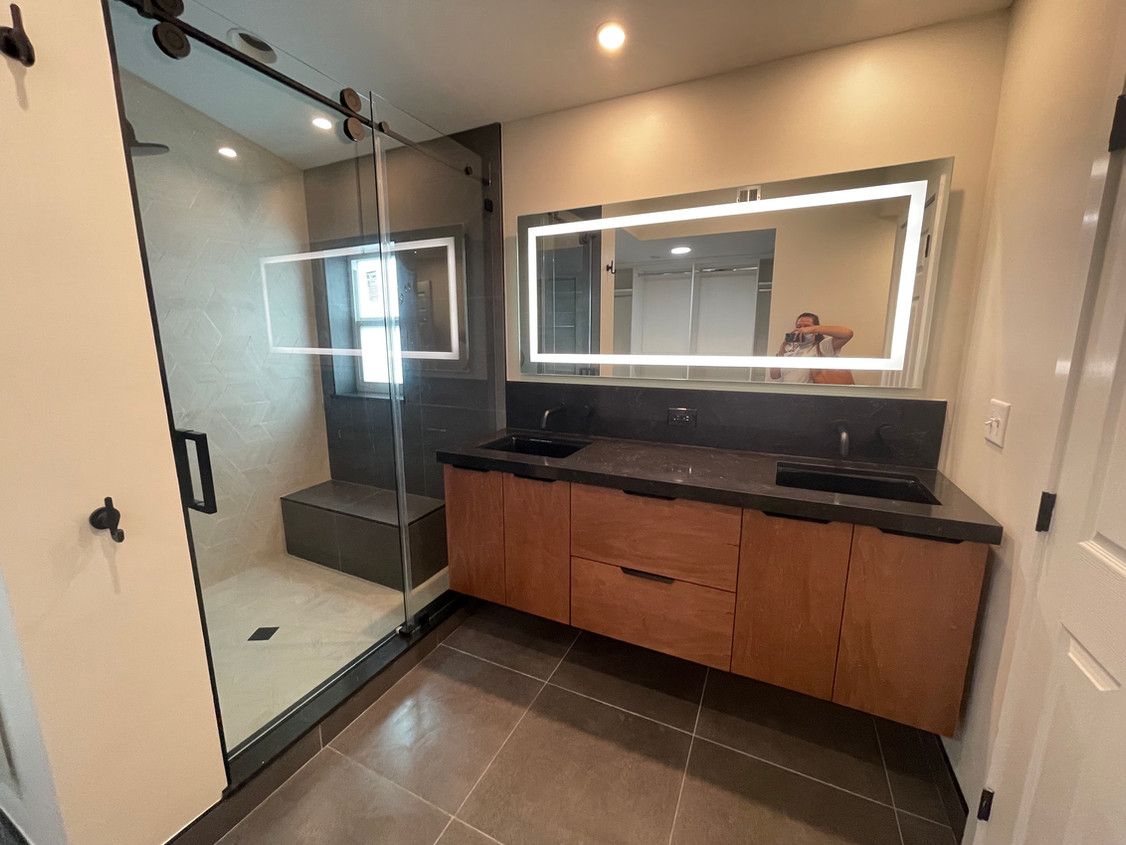 A bathroom with two sinks , a shower and a large mirror.