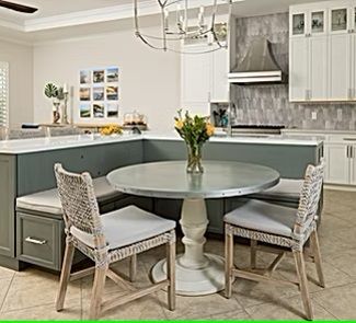 A kitchen with a table and chairs and a vase of flowers on the table.