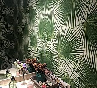 A bathroom with green leaves on the wall and a vanity.