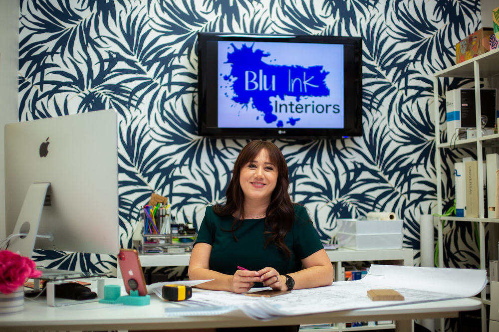 A woman is sitting at a desk in front of a television.