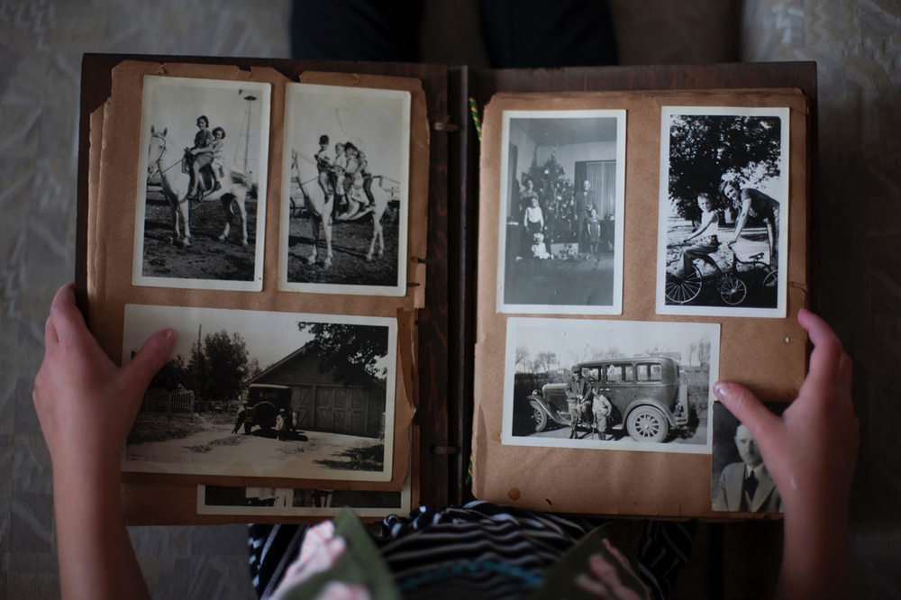 A person is holding a photo album filled with black and white photos.