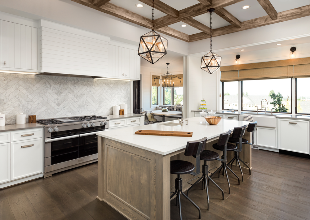 A kitchen with white cabinets , stainless steel appliances , and a large island.