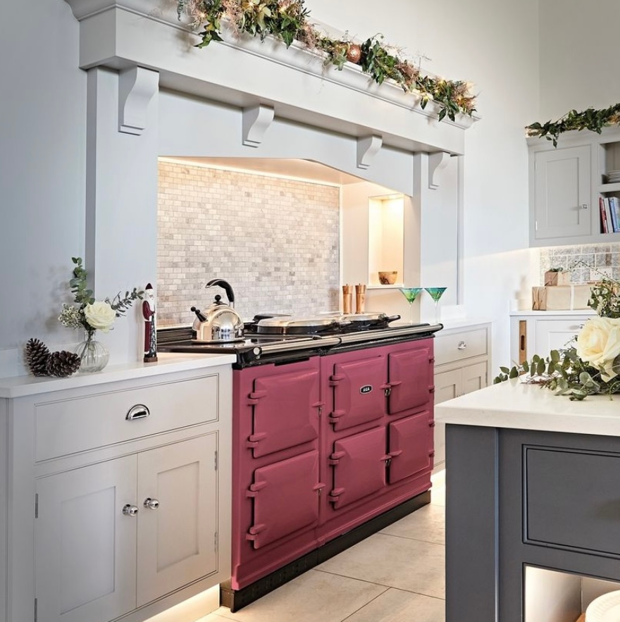 A kitchen with a pink stove and white cabinets