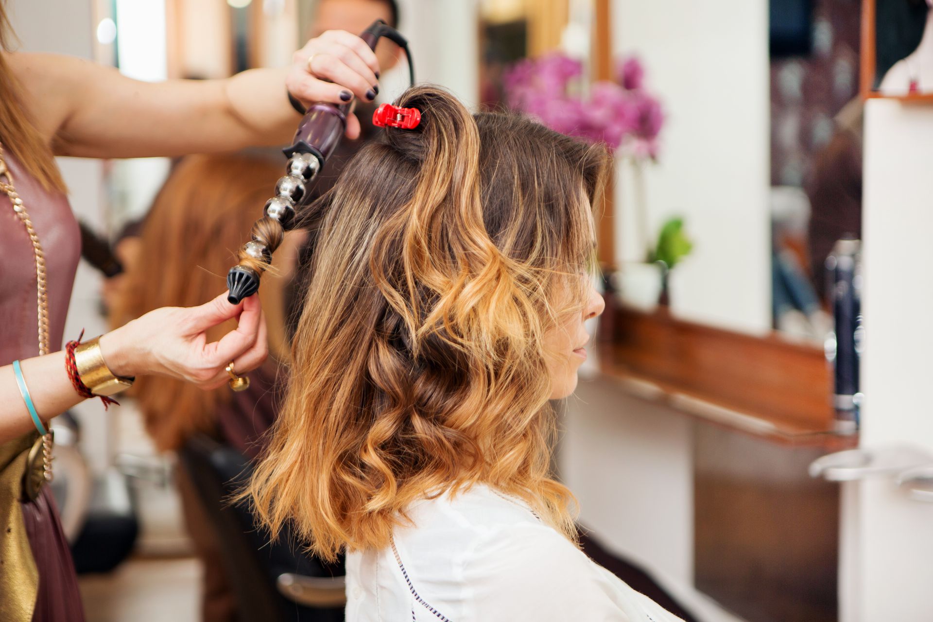 A woman is getting her hair done by a hairdresser in a salon
