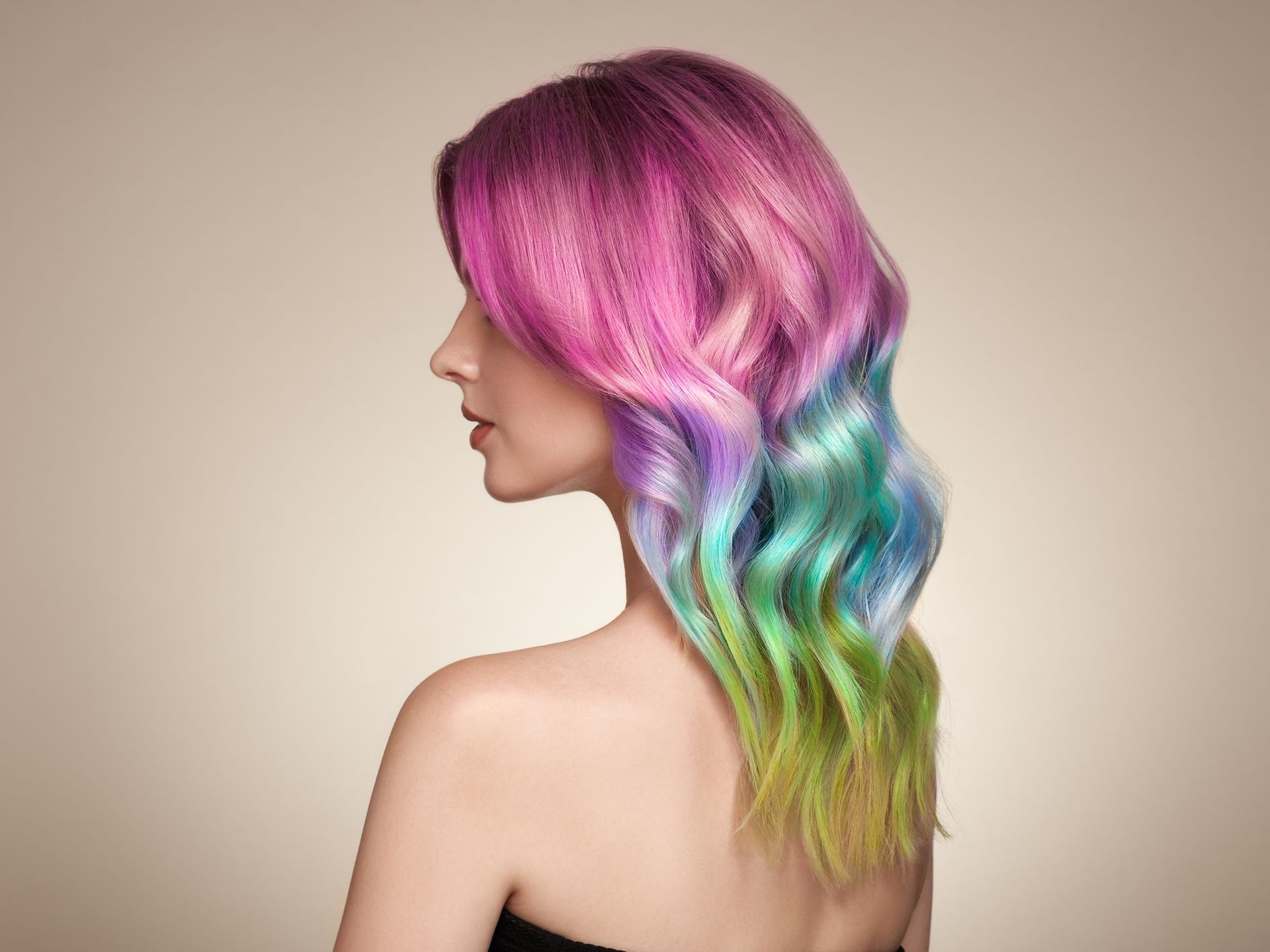 A woman with rainbow hair is wearing a black strapless top