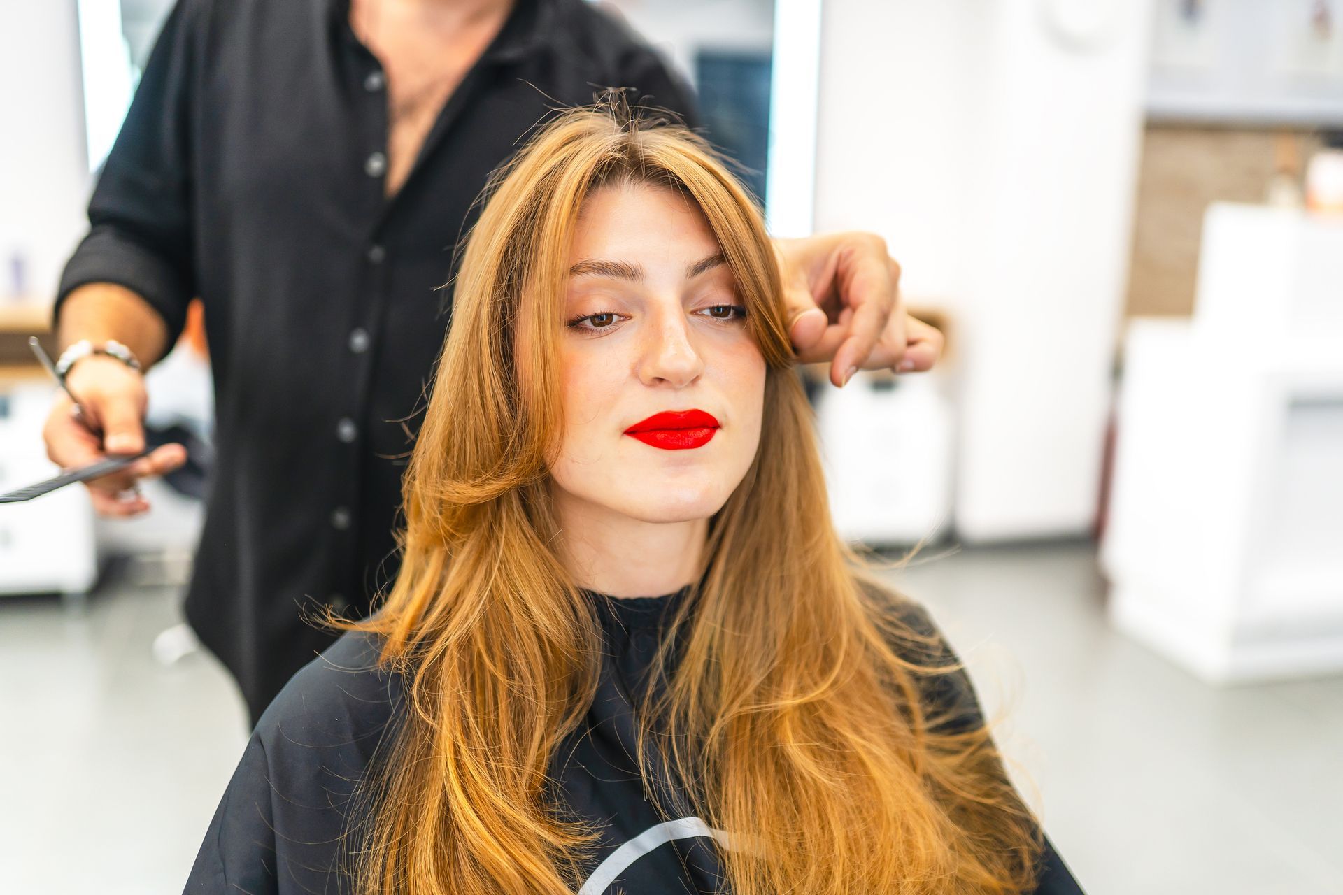 A woman is getting her haircut by a hairdresser in a salon