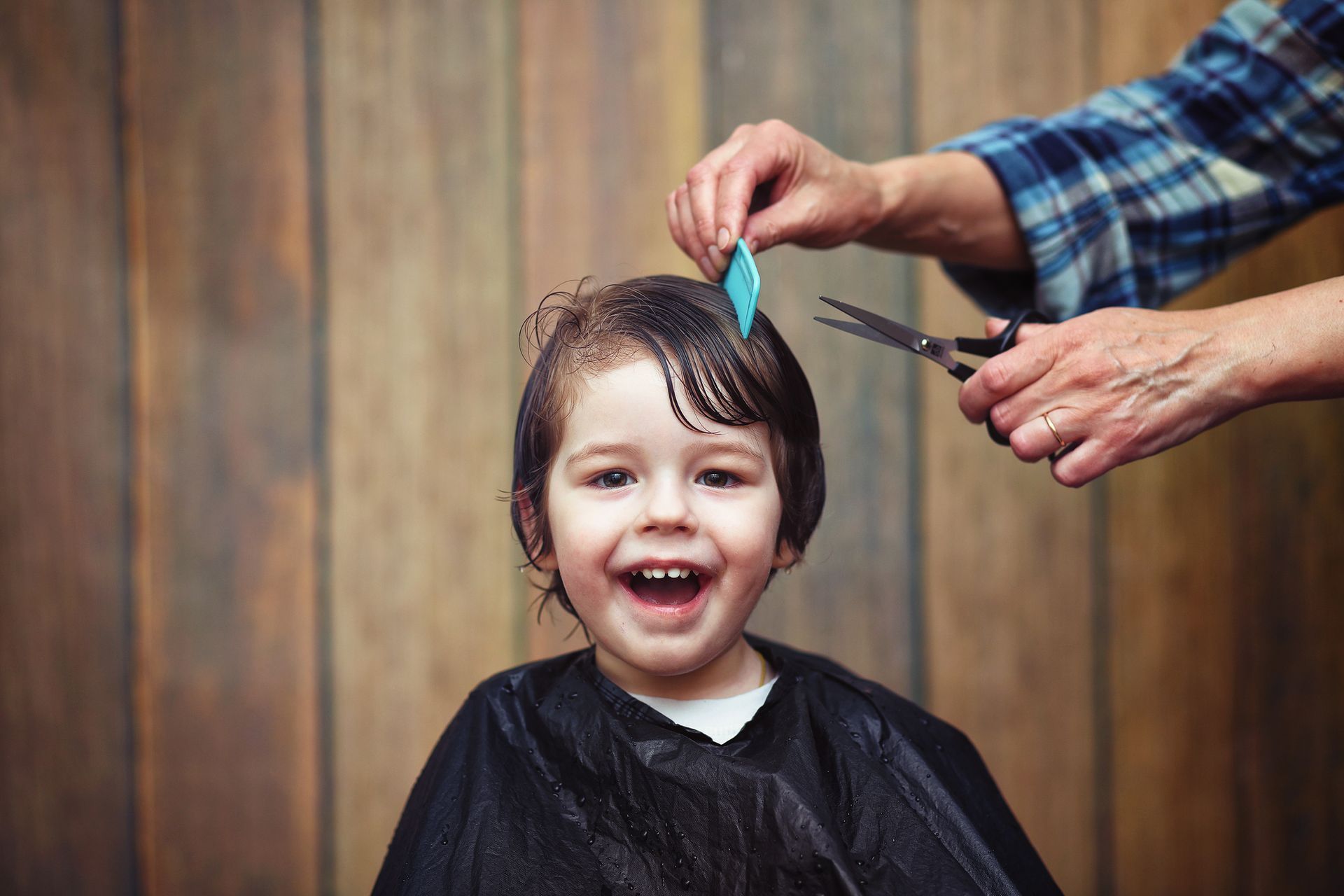 A little boy is getting his haircut by a hairdresser