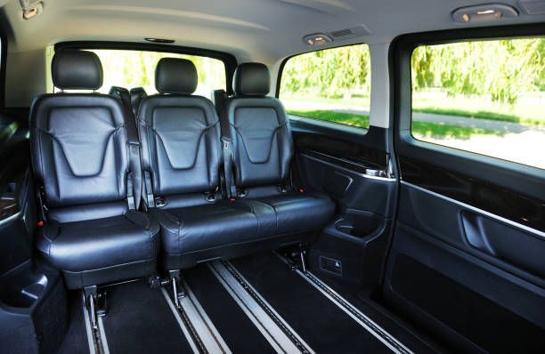 Interior view of a black minivan featuring sleek black seats, designed for a luxury limo rental service.

