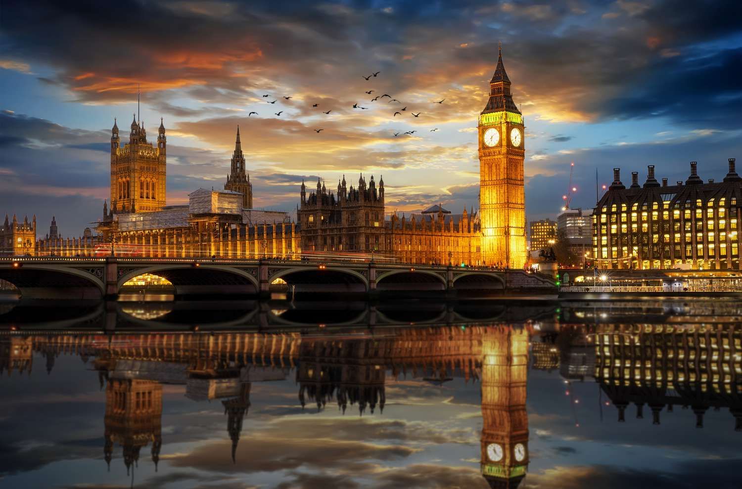 The big ben clock tower is reflected in the water in london at night.