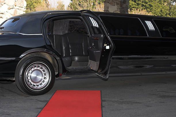  A man and woman pose for photos on a red carpet, celebrating a luxurious prom night experience.