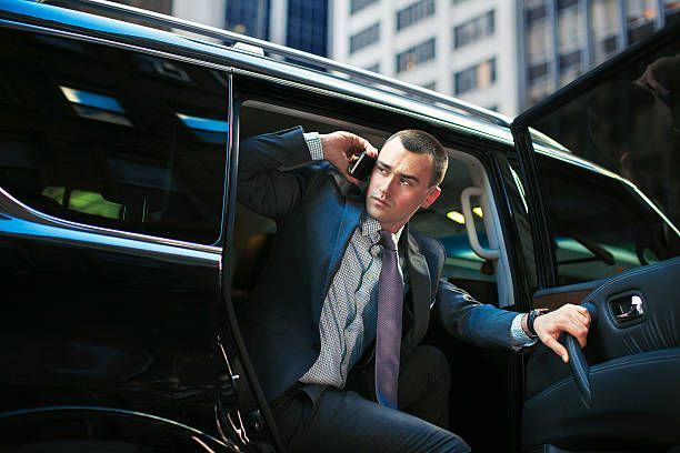  A man in a suit and tie is exiting a car, representing a limo rental service.