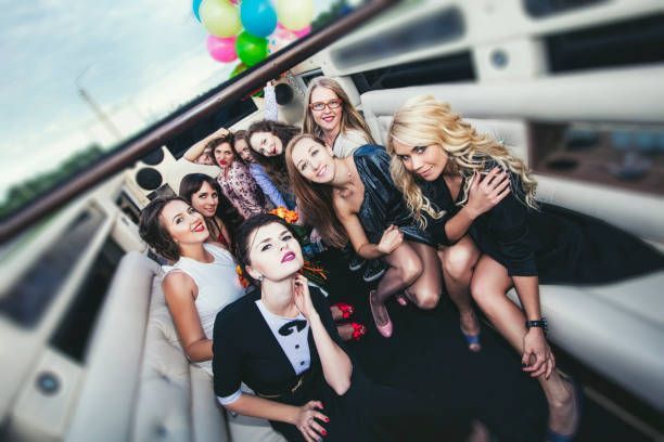 Group of women smiling and posing together inside a rented limo for a celebratory photo.
