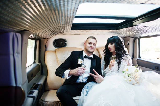 A bride and groom seated in a luxurious limo, celebrating their wedding day together.