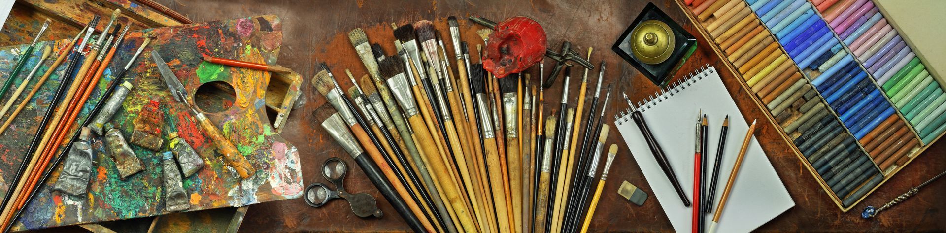 A bunch of brushes are sitting on a table next to a palette.