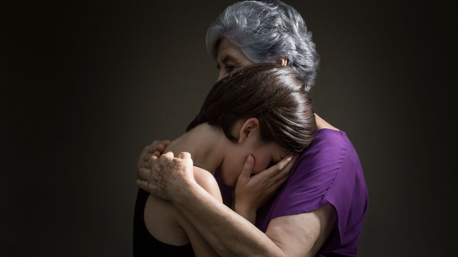 Elderly woman hugging a younger woman crying