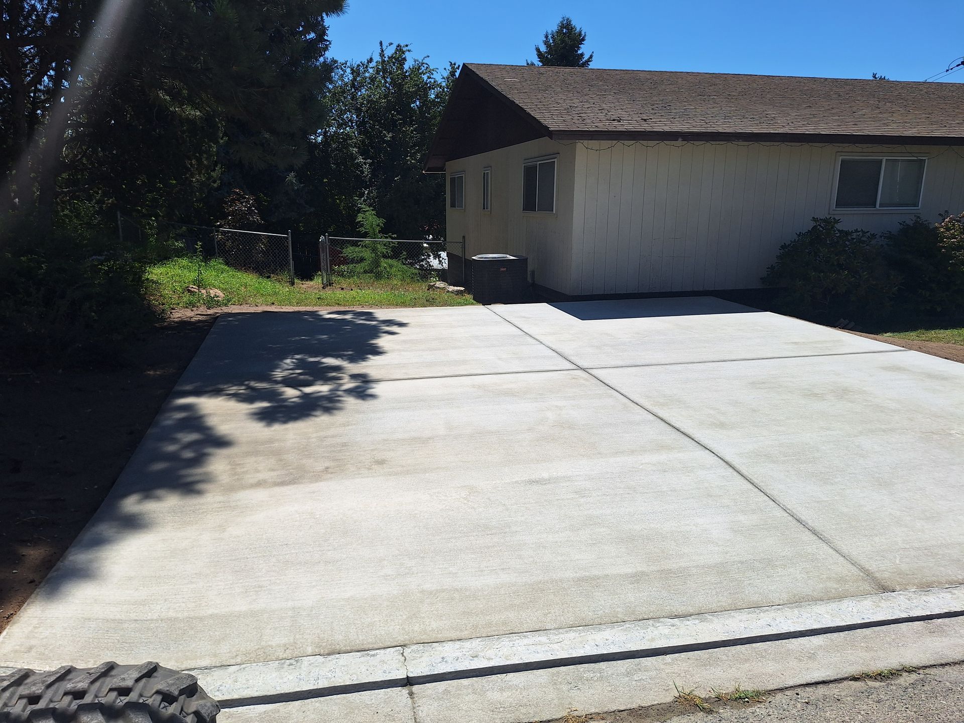 Concrete driveway in front of a one-story house on a sunny day.
