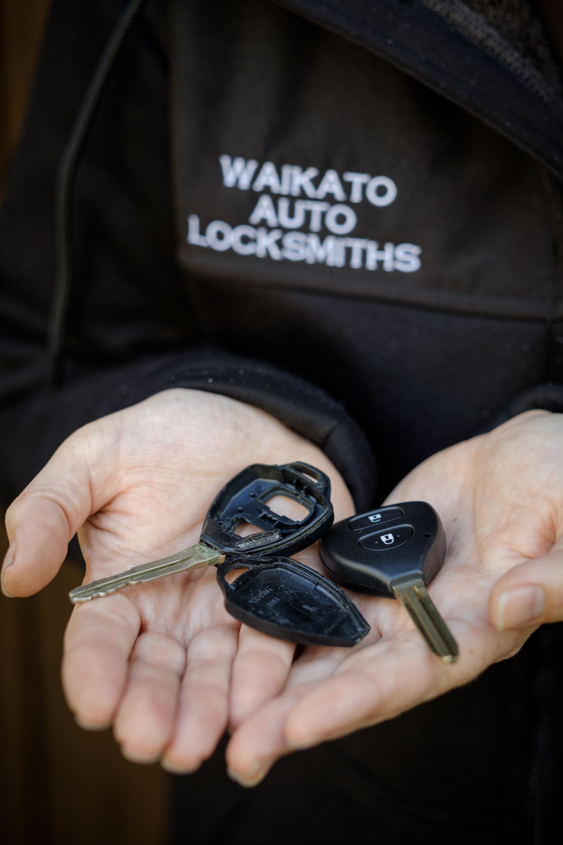 A car key is sitting on a black leather seat.