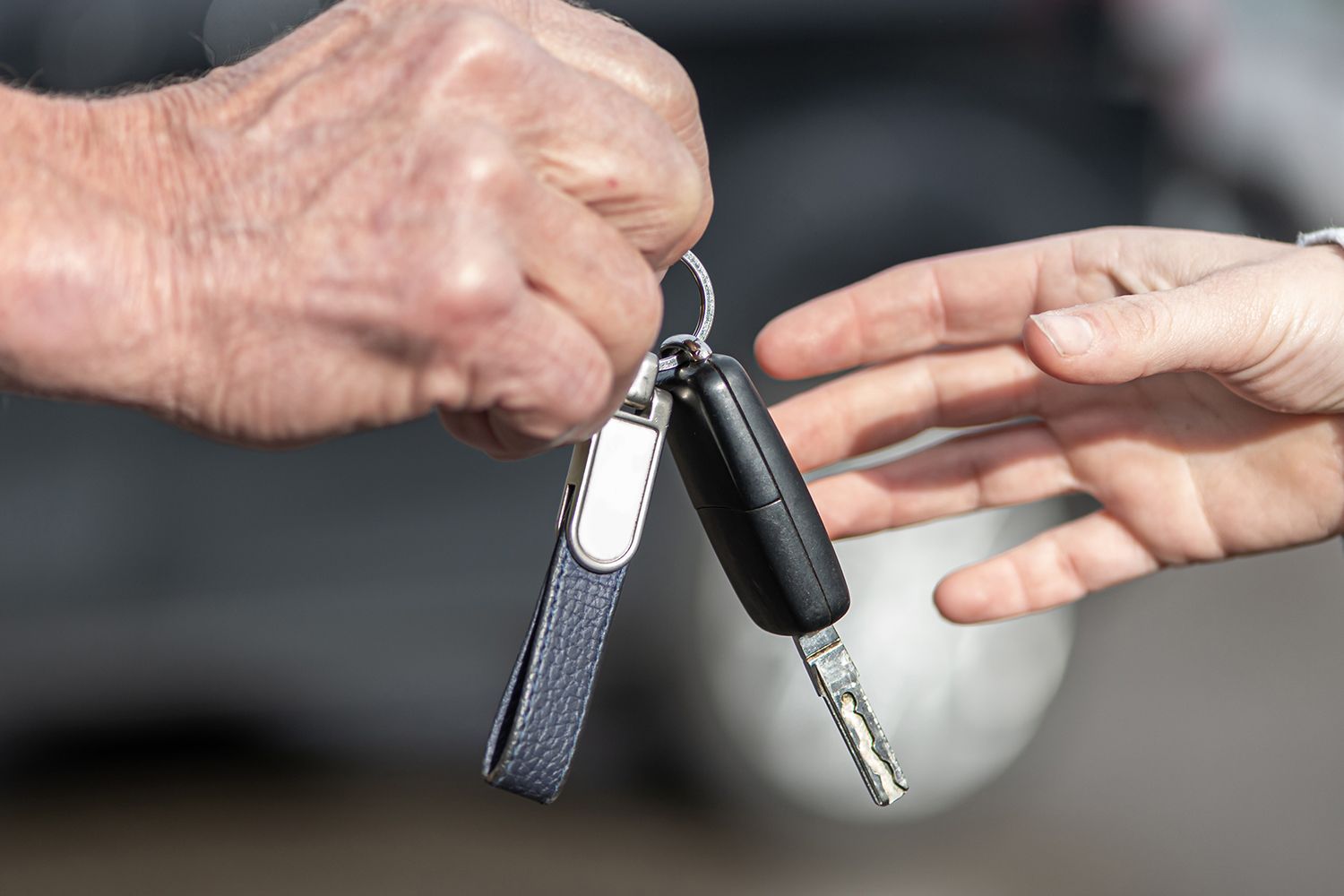 A man is handing a car key to a woman.