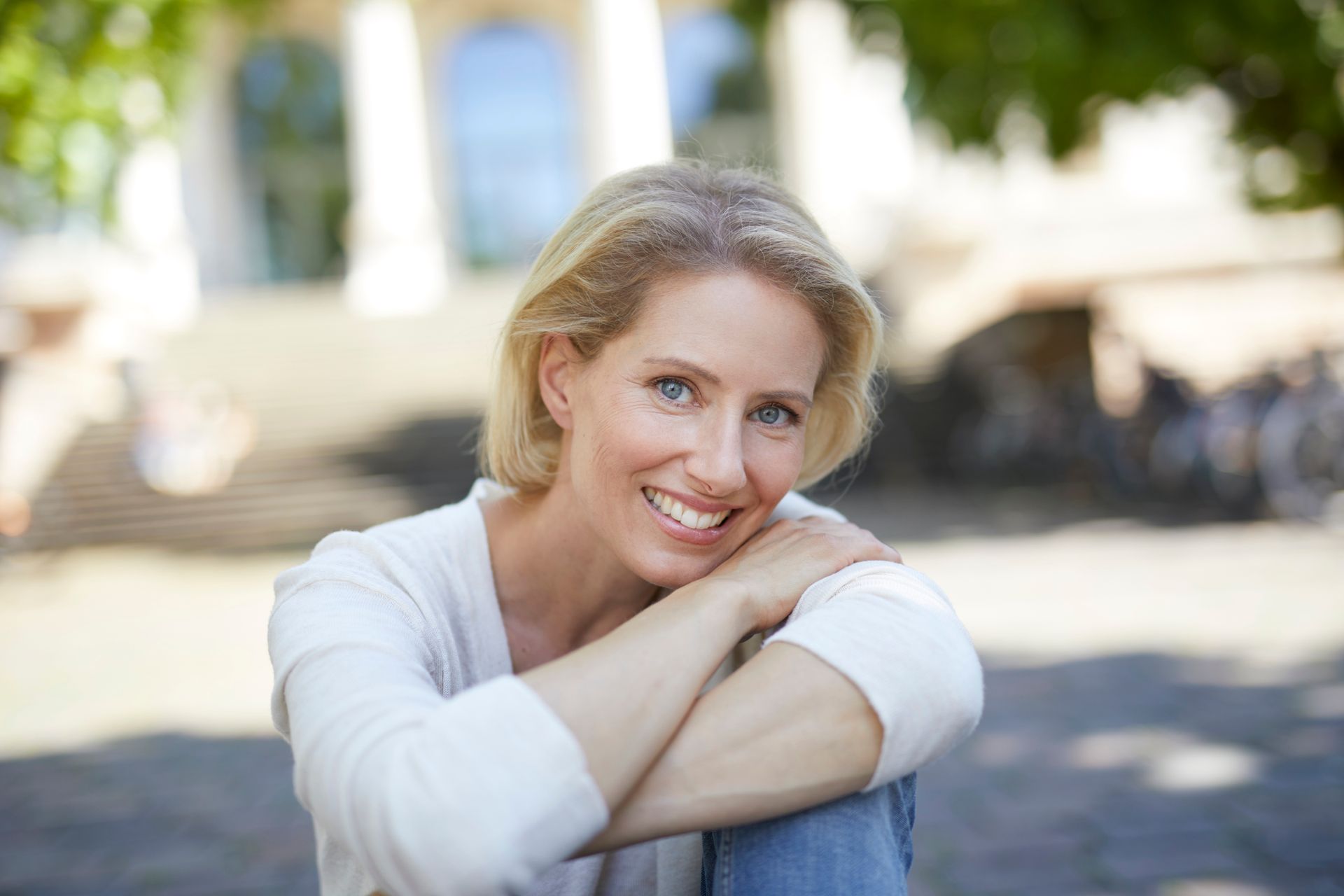 Middle aged woman sitting down, arms crossed, looking at camera