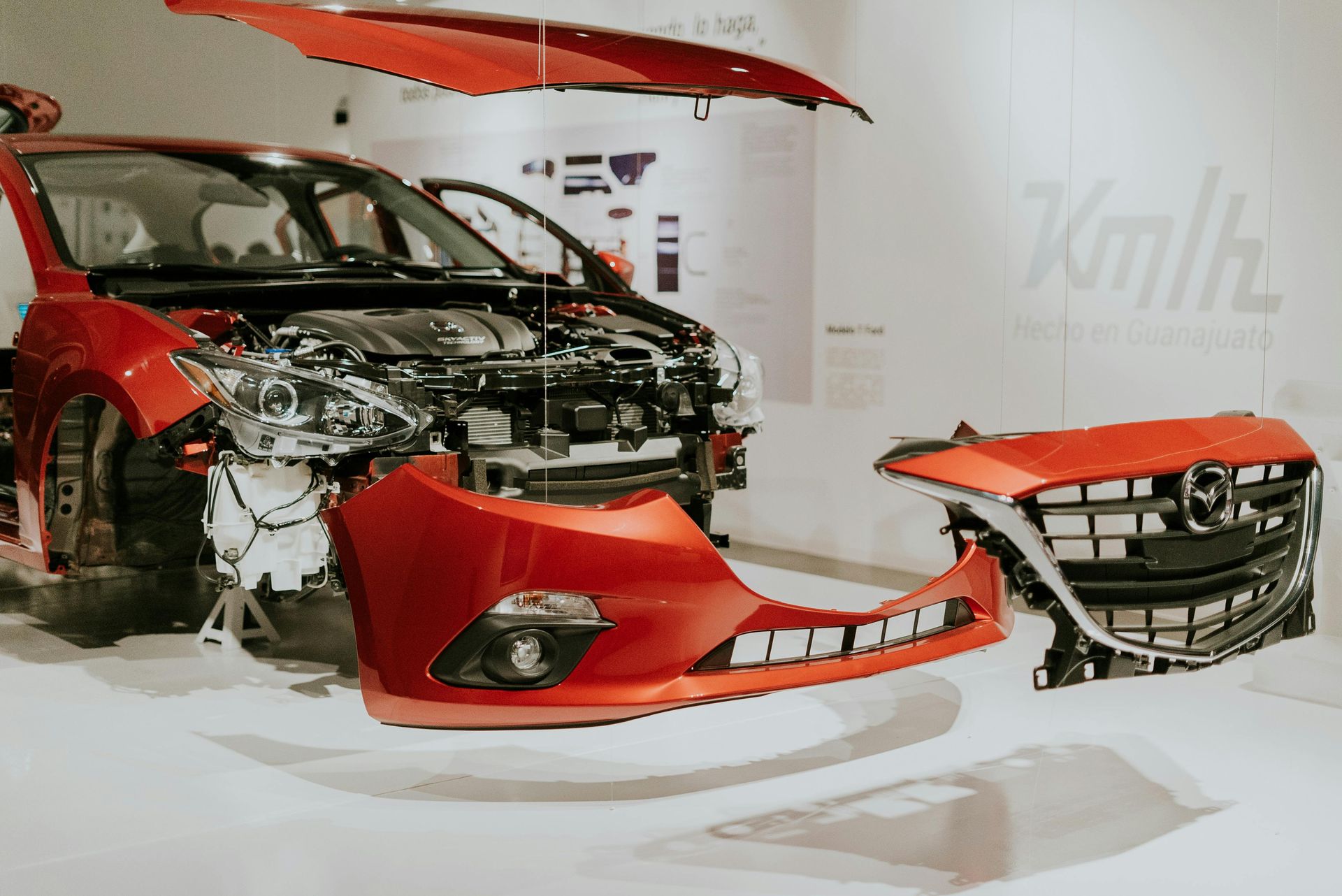The front end of a red car is being disassembled.