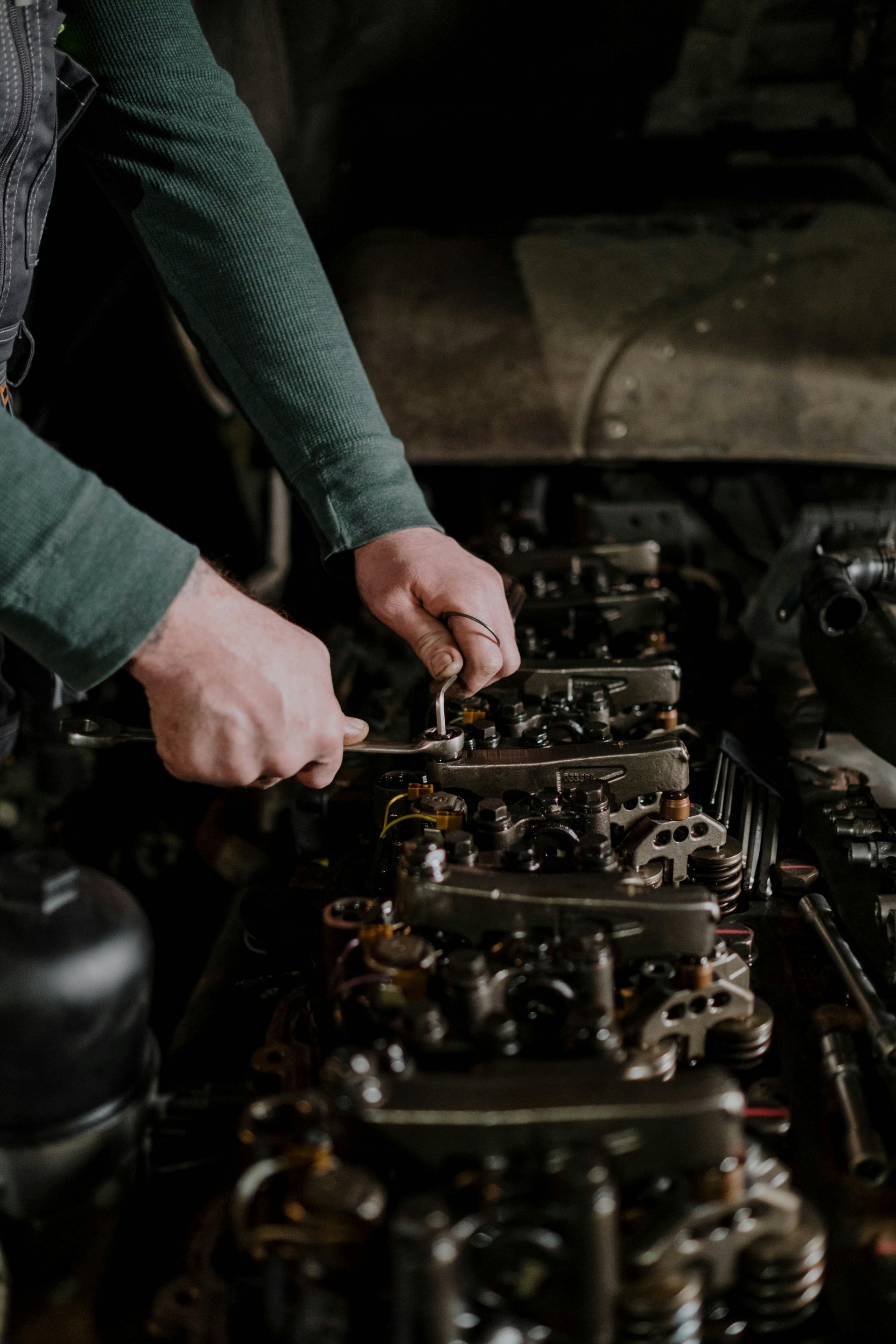 A man is working on a car engine with a wrench.