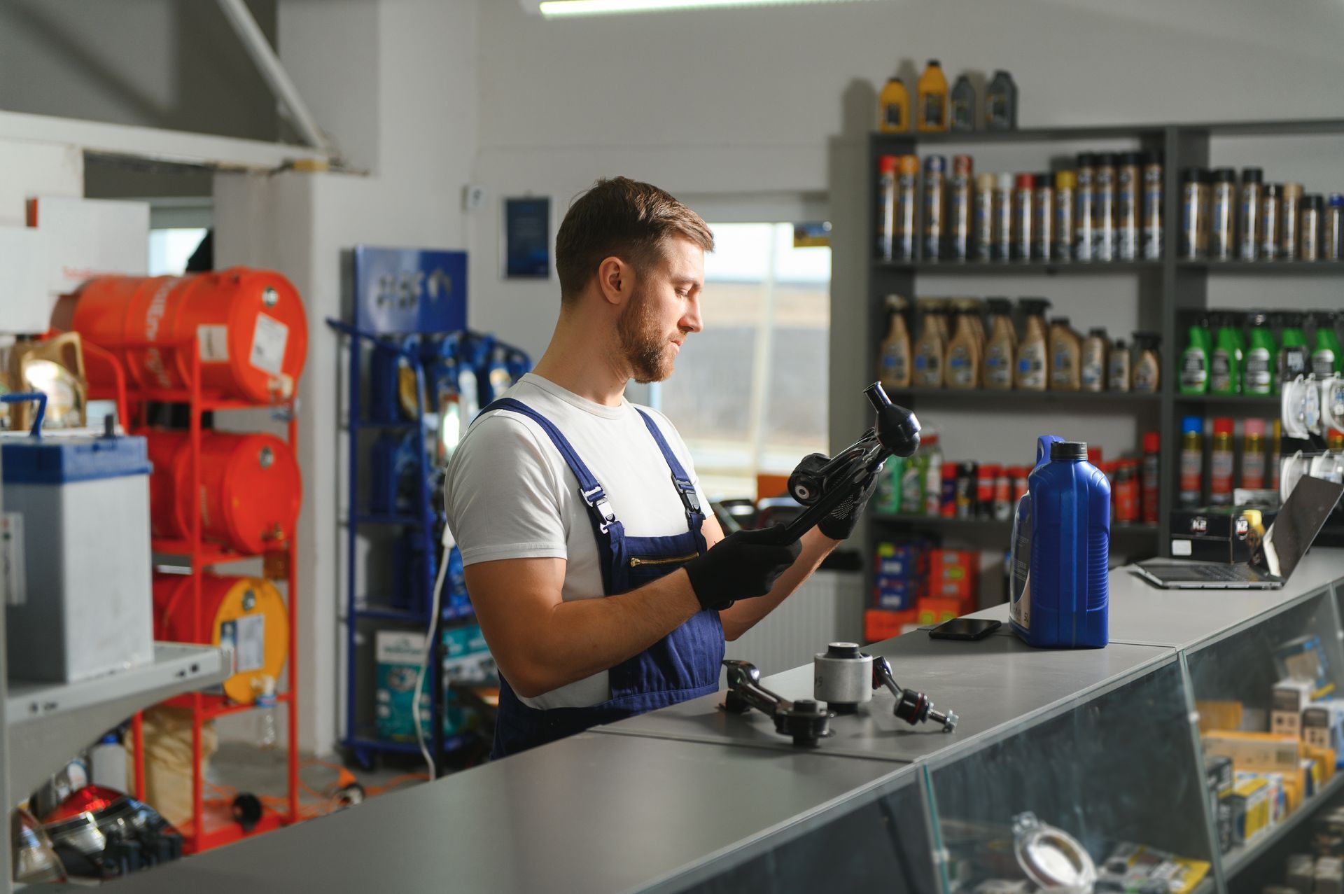 A man is standing at a counter in a car parts store looking at a tablet.