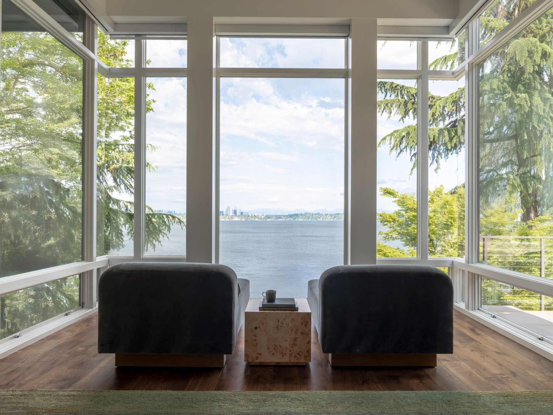 Two chairs face large windows with a view of a city skyline over water.