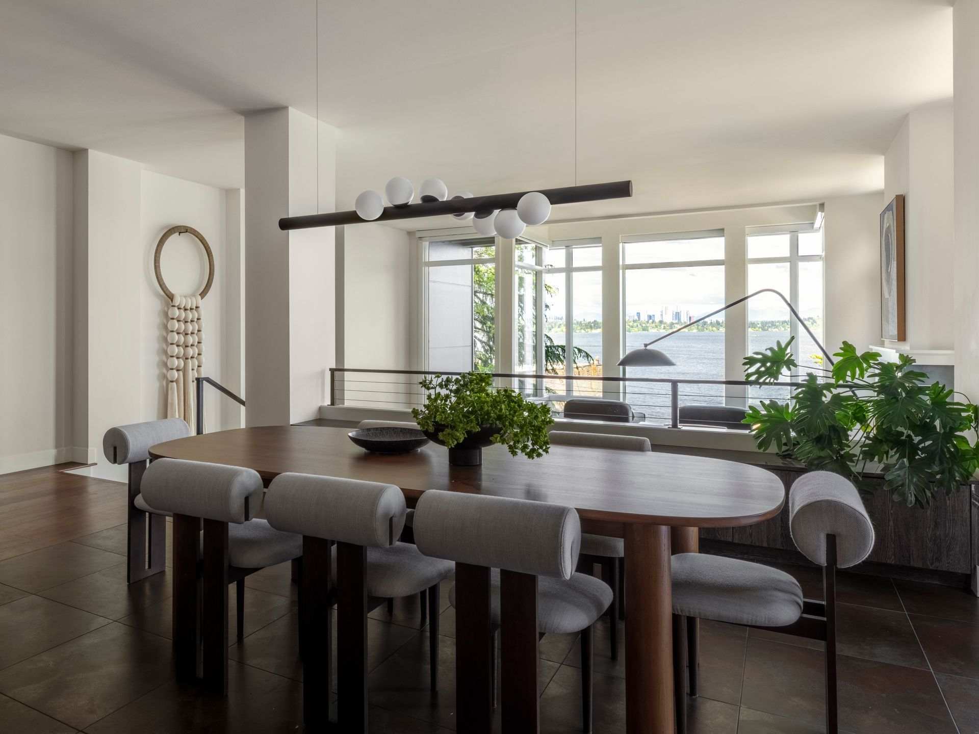 Dining room with oval wooden table, gray chairs, and modern light fixture.