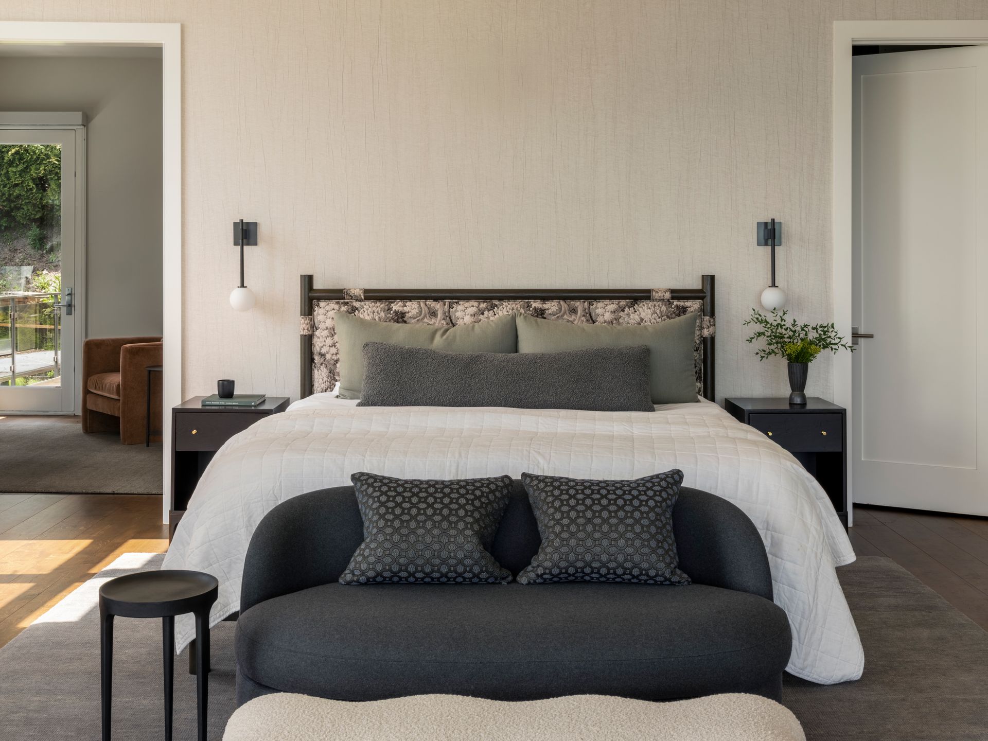Bedroom with a bed, bench, nightstands, and doorways. Neutral colors.